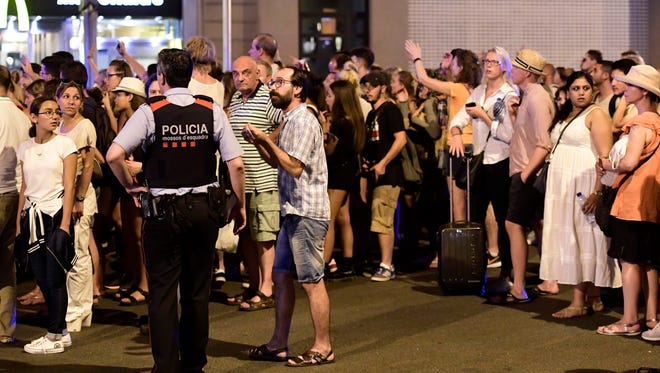 Tourists wait for the police to allow them to go back to their hotel on the Rambla boulevard after a van plowed into the crowd, killing at least 13 people and injuring around 100 others is towed away from the Rambla in Barcelona on Aug. 18, 2017.
