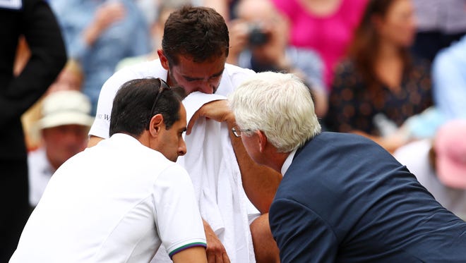 An emotional Marin Cilic is given assistance during match.