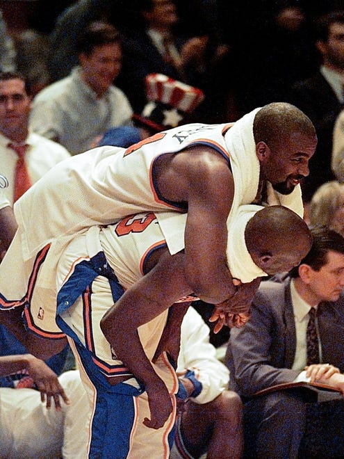Knicks' Charles Oakley jumps on the back of teammate Gary Grant.