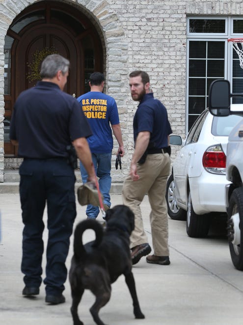 A police dog with a fire marshall from Anderson, Ind. enters the Zionsville home of Subway spokesperson Jared Fogle along with other law enforcement, including the U.S. Postal Inspection Police, during a morning-long investigation at Fogle's home in the 4500 block of Woods Edge Drive in the Austin Oaks subdivision on Tuesday morning, July 7, 2015.