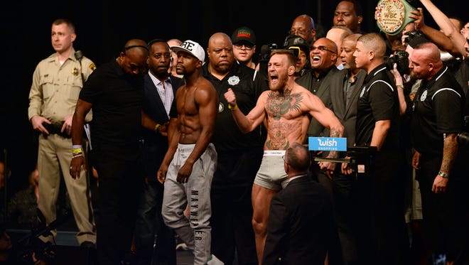 Floyd Mayweather Jr. (left) and Conor McGregor (right) pose for photos during weigh-ins for their upcoming boxing match at T-Mobile Arena.