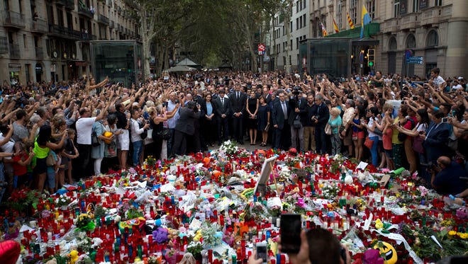 Spain's King Felipe, centre, stands with Queen Letizia and Catalonia regional President Carles Puigdemont, center, at a memorial tribute of flowers, messages and candles to the van attack victims in Las Ramblas promenade, Barcelona, Spain on Aug. 19, 2017. Authorities in Spain and France pressed the search Saturday for the supposed ringleader of an Islamic extremist cell that carried out vehicle attacks in Barcelona and a seaside resort, as the investigation focused on links among the Moroccan members and the house where they plotted the carnage.