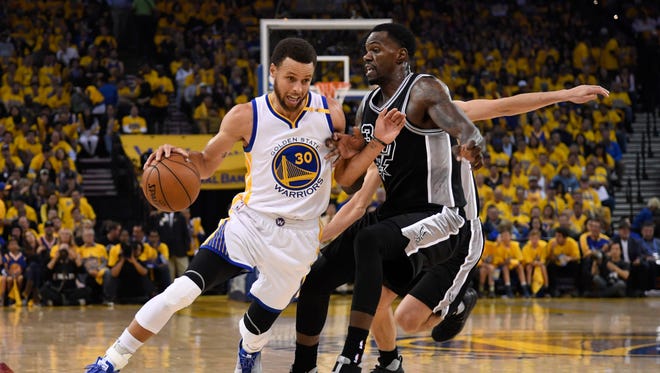 Golden State Warriors guard Stephen Curry dribbles the basketball against San Antonio Spurs center Dewayne Dedmon during the first quarter in Game 2 of the Western Conference finals.