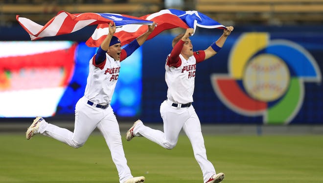 Hiram Burgos and Kike Hernandez carry Puerto Rico's flag as they celebrate their victory over the Netherlands.