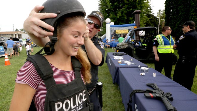 Saukville Reserve Police Officer Steve Peterson helps Melissa Anewenter of Port Washington into protective tactical equipment at the department' display during Saukville's National Night Out at Grady Park on Aug. 15.