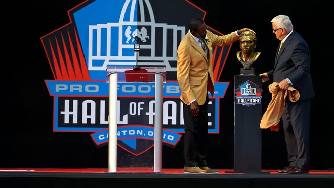 Kenny Easley stands with Tommy Rhodes (right) and his bust during the 2017 Pro Football Hall of Fame enshrinement at Tom Benson Hall of Fame Stadium.