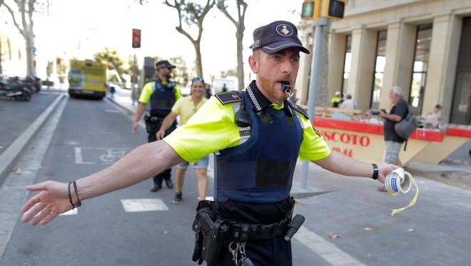 A police officer cordons off a street in Barcelona, Spain, Aug. 17, 2017. Police in the northern Spanish city of Barcelona say a white van has jumped the sidewalk in the city's historic Las Ramblas district, injuring several people.