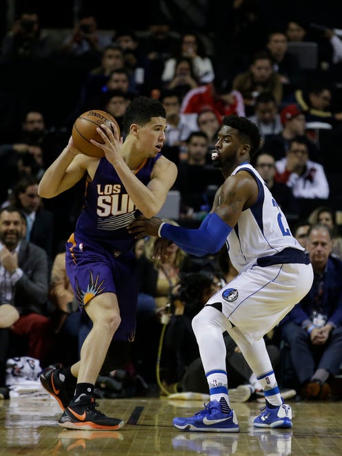Phoenix Suns Devin Booker holds the ball back, under pressure from Dallas Mavericks Wesley Matthews in the first half of their regular-season NBA basketball game in Mexico City, Thursday, Jan. 12, 2017.