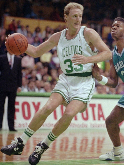 This is a November 1991 file photo of Boston Celtic legend Larry Bird driving against Charlotte Hornet forward J.R. Reid in a game at the Boston Garden in Boston.