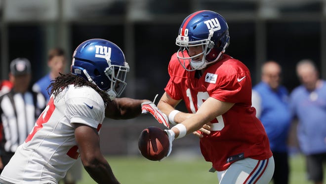 New York Giants quarterback Eli Manning (10) hands off to running back Paul Perkins (28) works out during NFL football training camp, Thursday, Aug. 3, 2017, in East Rutherford, N.J.