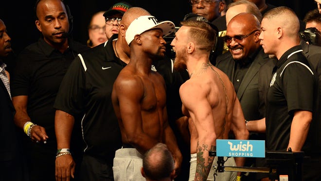 Floyd Mayweather Jr. (left) and Conor McGregor (right) face off during weigh-ins for their upcoming boxing match at T-Mobile Arena.