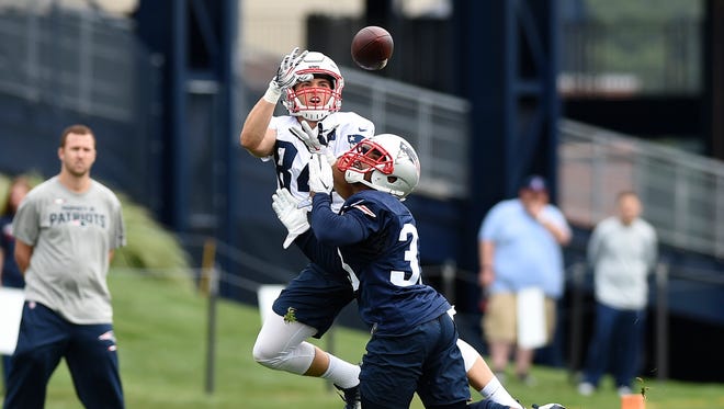 New England Patriots wide receiver Austin Carr (84) makes a catch while running back Dion Lewis (33) defends during training camp at Gillette Stadium.