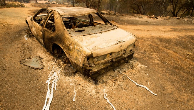 A scorched car rests next to a residence leveled by the Detwiler fire near Mariposa, Calif.