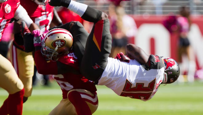 San Francisco 49ers cornerback Tramaine Brock flips Tampa Bay Buccaneers running back Antone Smith on a tackle during the first quarter.