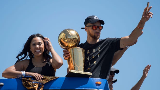 2017: Curry waves to the crowd holding the championship trophy next to wife Ayesha Curry.