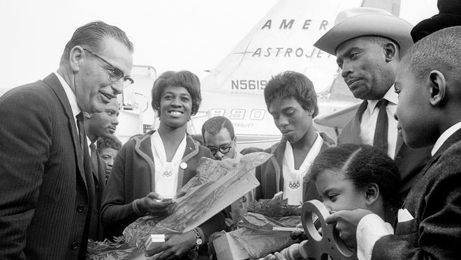 Flowers and a giant key to the city are presented to Tennessee A&I State 's Olympic heroes Edith McGuire, second from left, Wyomia Tyus, and Coach Ed Temple, right, by Paul Startup, left, representative of Mayor Beverly Briley, as they arrive at the Nashville Municipal Airport Oct. 28, 1964. Looking on are Temple's children, Edwina and Lloyd Bernard, right.