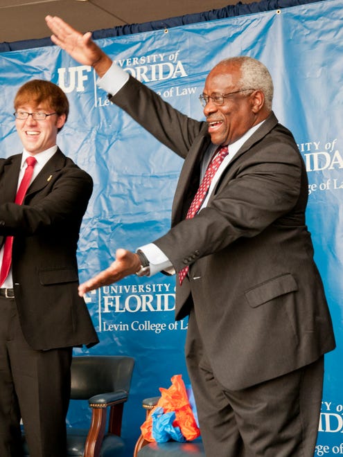 In this photo provided by the University of Florida, Thomas does the "gator chomp" with law school student Zack Smith at the end of his speech at the Levin College of Law on the University of Florida campus on Sept. 21, 2012, in Gainesville, Fla.