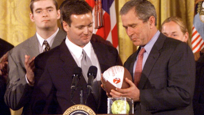 President George W. Bush looks at a game ball from the national championship game presented by  Oklahoma coach Bob Stoops in 2001.