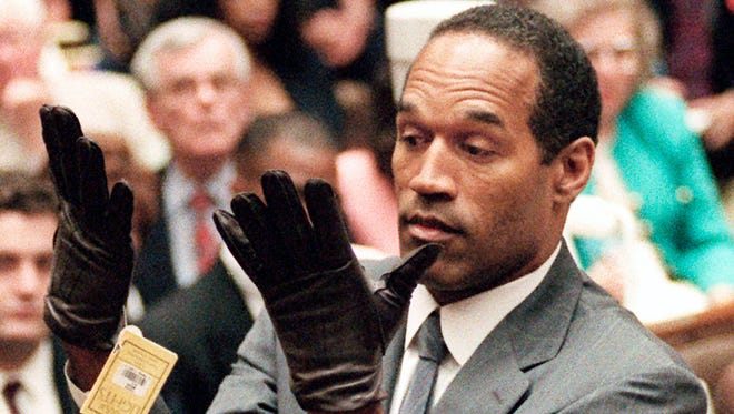 Simpson holds up his hands before the jury, trying on gloves during his trial in 1995.