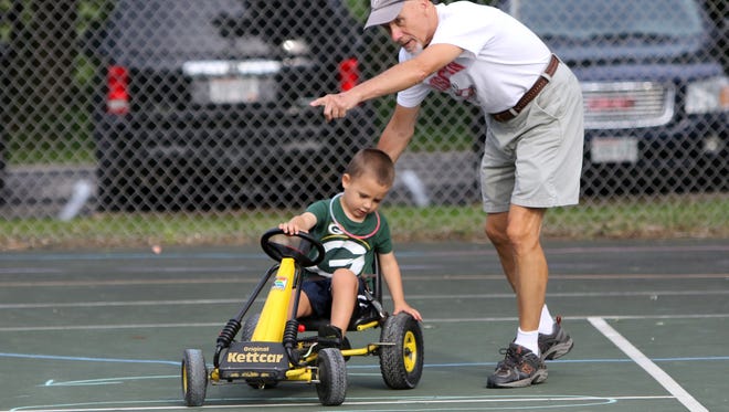 Bud Gorski of Mequon tries to get grandson Andrew Tadych, 3, onto the right path of a pedal car course created by Boy Scout Troop 868 for Saukville's National Night Out at Grady Park on Aug. 15.