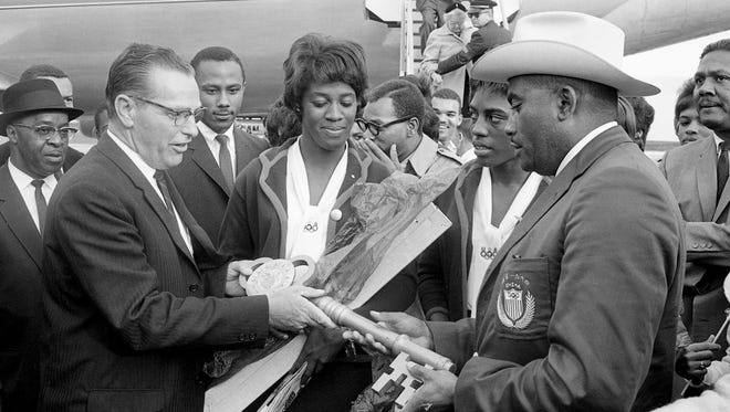 Flowers and a giant key to the city are presented to Tennessee A&I State 's Olympic heroes Edith McGuire, middle, Wyomia Tyus, second from right and Coach Ed Temple, right, by Paul Startup, left, representative of Mayor Beverly Briley, as they arrive at the Nashville Municipal Airport Oct. 28, 1964.