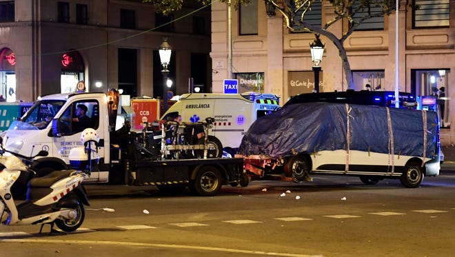 The van who plowed into the crowd, killing at least 13 people and injuring around 100 others is towed away from the Rambla in Barcelona on Aug. 18, 2017. A driver deliberately rammed a van into a crowd on Barcelona's most popular street on Aug. 17, 2017 killing at least 13 people before fleeing to a nearby bar, police said.  Officers in Spain's second-largest city said the ramming on Las Ramblas was a "terrorist attack". The driver of a van that mowed into a packed street in Barcelona is still on the run, Spanish police said.