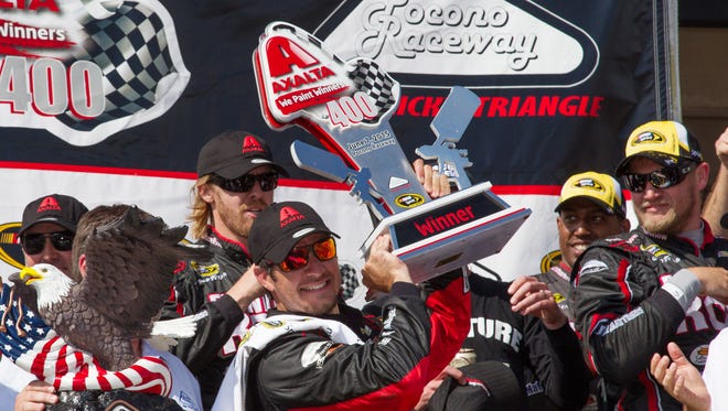 Martin Truex Jr. raises the winner's trophy after snapping a 69-race winless streak by taking the Axalta We Paint Winners 400 at Pocono Raceway on June 7, 2015.