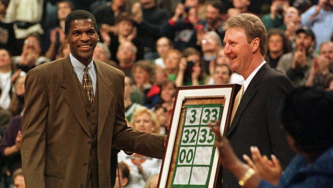 Former Celtics star Robert Parish, left, looks towards his family as he stands with former teammate Larry Bird, right, and their banner during Parish's number retirement ceremony in Boston Sunday, Jan. 18, 1998.