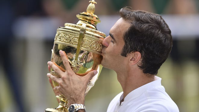 Roger Federer kisses the winner's trophy after beating Marin Cilic for his eighth Wimbledon title and 19th Grand Slam.