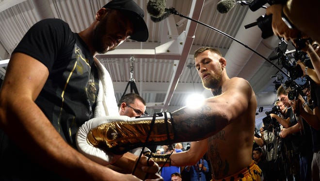 Conor McGregor has his gloves tied during a media workout in preparation for his fight against Floyd Mayweather at UFC Performance Institute.