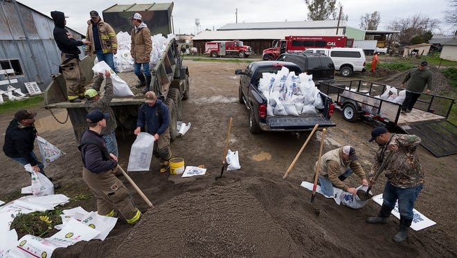 Members of the Maxwell Fire Department fill sandbags as the town prepares for another storm, Sunday, Feb. 19, 2017, in Maxwell, Calif.