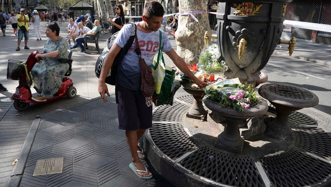 A man places flowers at the Canaletas fountain on the Rambla boulevard on Aug. 18, 2017.