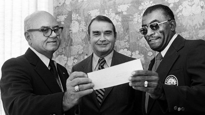 Tennessee State women's track coach Ed Temple, right, accepts a $1,000 check from Walter Nipper, left, of Nashville Sporting Goods while Charles Kane, chairman and president of Third National Bank observes Sept. 25, 1976. Nipper's donation for the new track fund brought the total to $85,000 in the drive with a goal of $100,000.