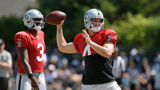 Oakland Raiders quarterback Derek Carr, right, throws as backup quarterback EJ Manuel, left, looks on during training camp Tuesday, Aug. 8, 2017, in Napa, Calif.