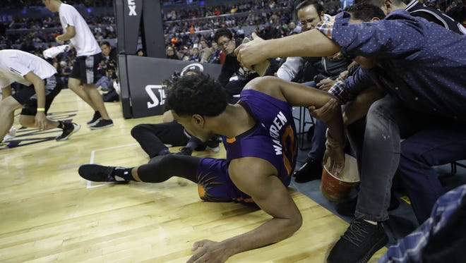 A fan grabs Phoenix Suns TJ Warren by the arm and tries to take a selfie, during the first half of a regular-season NBA basketball game with the Dallas Mavericks in Mexico City, Thursday, Jan. 12, 2017.
