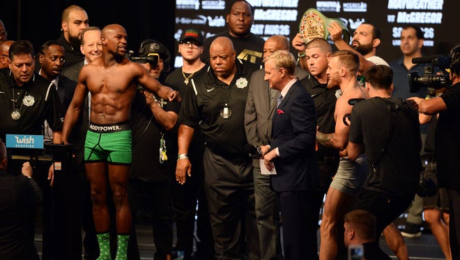 Floyd Mayweather Jr. (left) shouts at Conor McGregor (right) while weighing in for their upcoming boxing match at T-Mobile Arena.