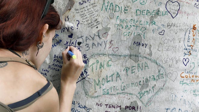 A woman writes a note on a tree of La Rambla, in Barcelona, Spain on Aug. 20, 2017.