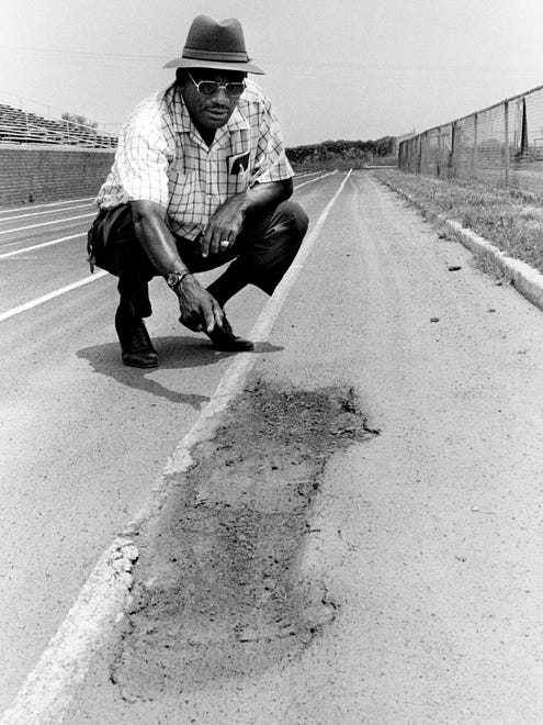 Tennessee State University women's track coach Ed Temple points to a hole that being there at least a year on the school's track July 9, 1976. Temple said the Tigerbelles program was in danger of ending if they don't get some quick help in building a new track.