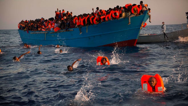 In this Monday, Aug. 29, 2016 file photo, migrants, most of them from Eritrea, jump onto the water from a crowded wooden boat as they are helped by members of an NGO during a rescue operation on the Mediterranean Sea, about 13 miles north of Sabratha, Libya.