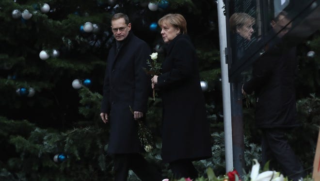 Mayor of Berlin Michael Mueller, left, and German Chancellor Angela Merkel arrive to lay flowers on Dec. 20, 2016, near where a truck crashed through a Christmas market the previous day.