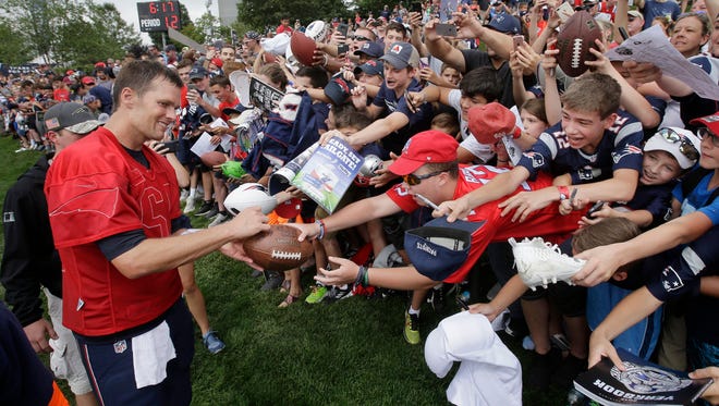 New England Patriots' Tom Brady, left, signs autographs for fans at NFL football training camp, Thursday, Aug. 3, 2017, in Foxborough, Mass. Brady turned 40 years old Thursday.