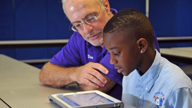 Dave Brown, with United Way and Rolling Readers, mentors 3rd grader Vahreion Krikman, age 9. United Way of Brevard has teamed up with Emma Jewel Charter Academy in Cocoa to provide the MyON electronic books program.