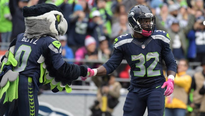 Seahawks running back Christine Michael (32) shakes hands with mascot Blitz after scoring a touchdown in the fourth quarter against the Falcons.