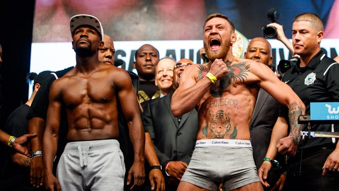 Conor McGregor (right) reacts alongside Floyd Mayweather during weigh-ins for their boxing match at T-Mobile Arena.