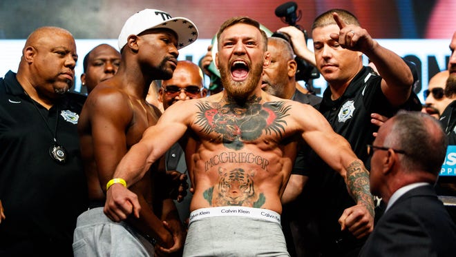 Conor McGregor (right) reacts alongside Floyd Mayweather during weigh-ins for their upcoming boxing match at T-Mobile Arena.