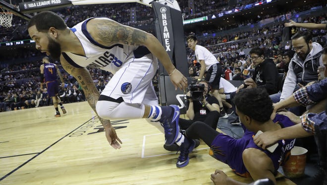 Dallas Mavericks Deron Williams returns to the court, along with Phoenix Suns TJ Warren, on the ground, after falling during the first half of their regular-season NBA basketball game in Mexico City, Thursday, Jan. 12, 2017.