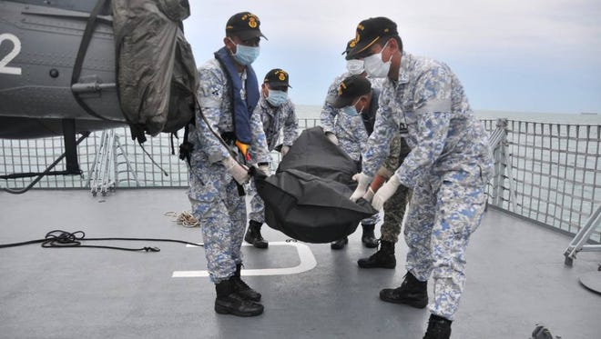 A handout photo made available by the Royal Malaysian Navy shows navy personnel with a body bag containing the remains of one of the missing sailors from the US guided-missile destroyer USS John S. McCain off the coast of Malaysia,  Aug. 22, 2017.