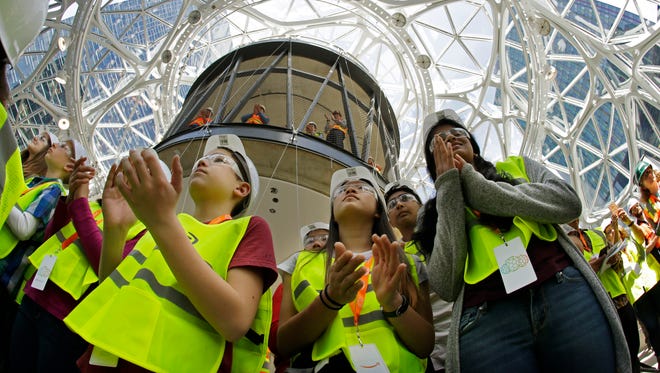 Students and others from the Environmental and Adventure School in Kirkland, Wash., applaud during a ceremony for the planting of an Australian Tree Fern inside the Amazon Spheres on May 4, 2017, in Seattle. The plant will be the first of thousands that will eventually grow in the unique glass domes, which are scheduled to open in 2018 on Amazon.com's downtown campus and will be used by employees to work and relax in a lush environment with a constant 72-degree temperature.