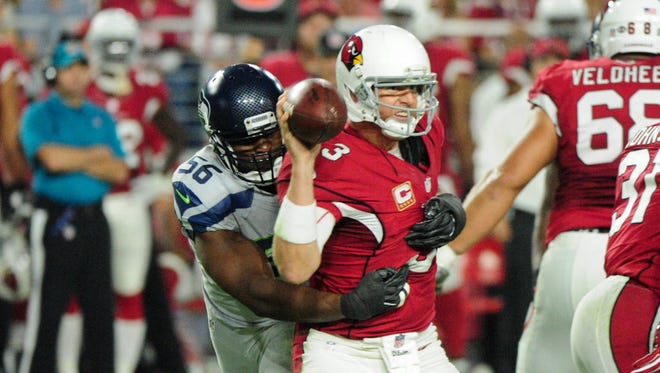 Cardinals quarterback Carson Palmer (3) throws while being tackled by Seahawks defensive end Cliff Avril (56).