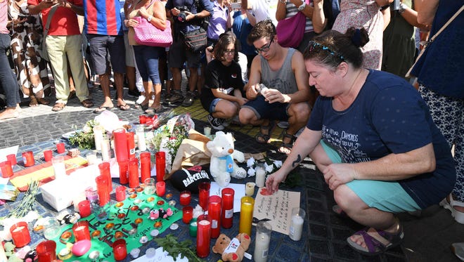 People gather next to flowers, candles and other items set up on the Las Ramblas boulevard in Barcelona as they pay tribute to the victims of the Barcelona attack on Aug. 18, 2017.
